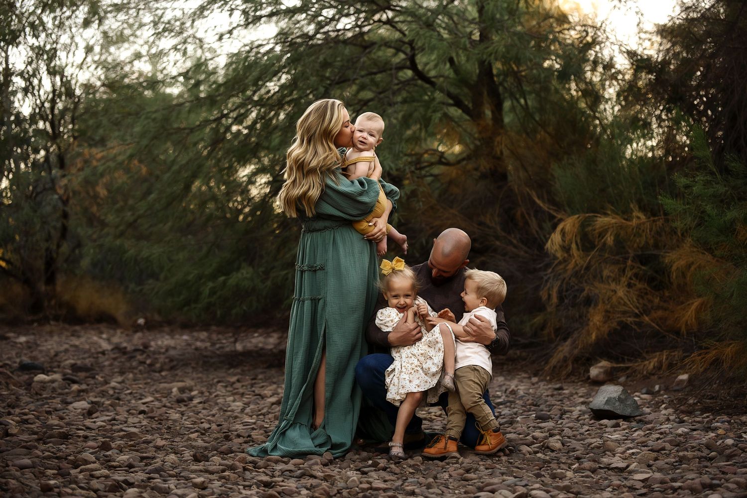 Mother in emerald gown with three young children during golden hour desert family portrait.