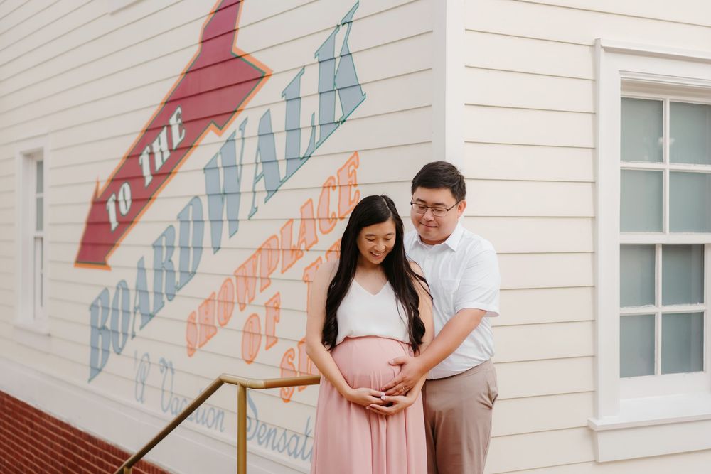 A couple shares a tender moment together against a white wall with colorful geometric designs.