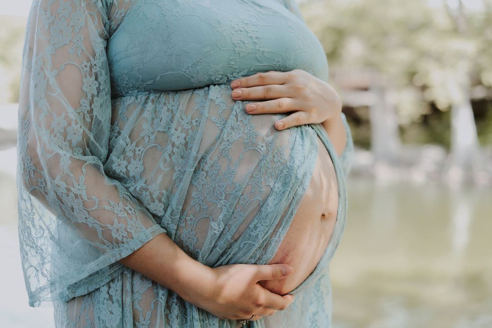 A series of maternity photos showing a teal lace dress against a soft outdoor background with cherry blossoms.