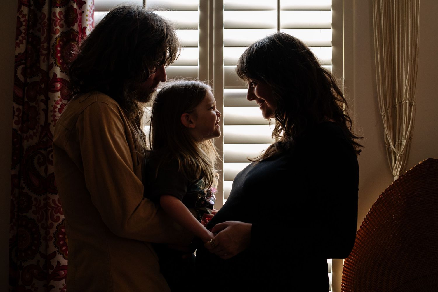Family portrait in a greenhouse surrounded by tropical plants and natural light.
