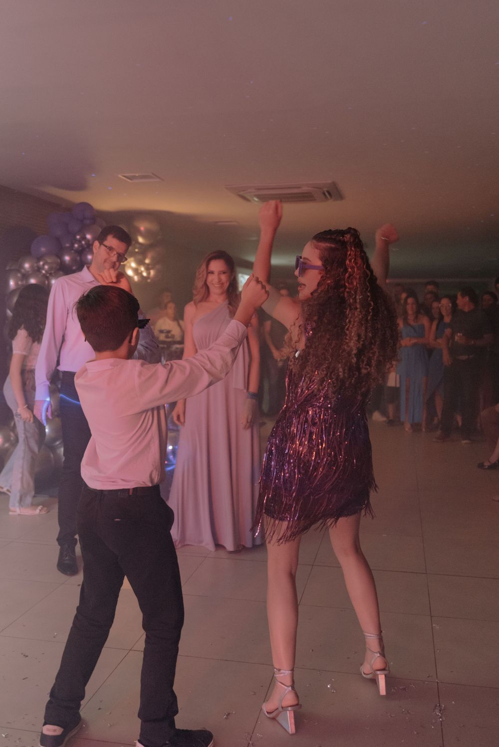 Party guests dancing together at an event with festive lighting and decor.