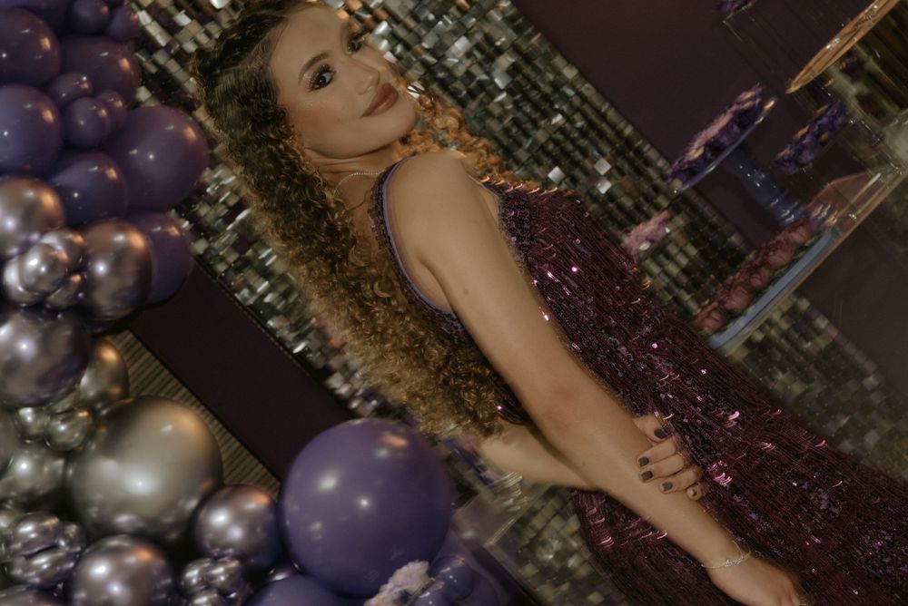 Elegant party scene with sparkling dress against silver and purple balloon decorations.