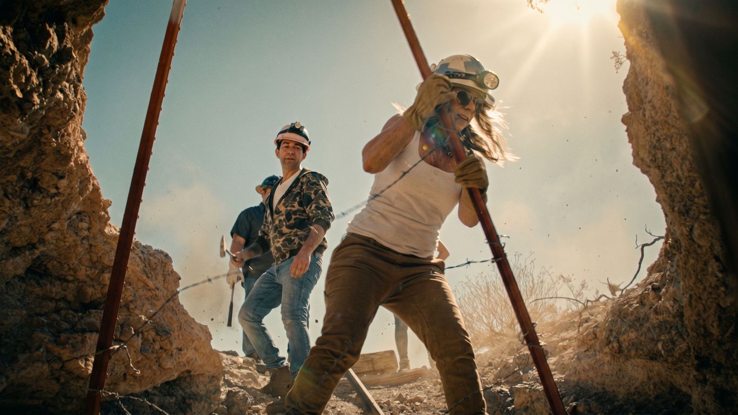 Gold Blooded production still: silhouetted figures beside a mine headframe at sunset.