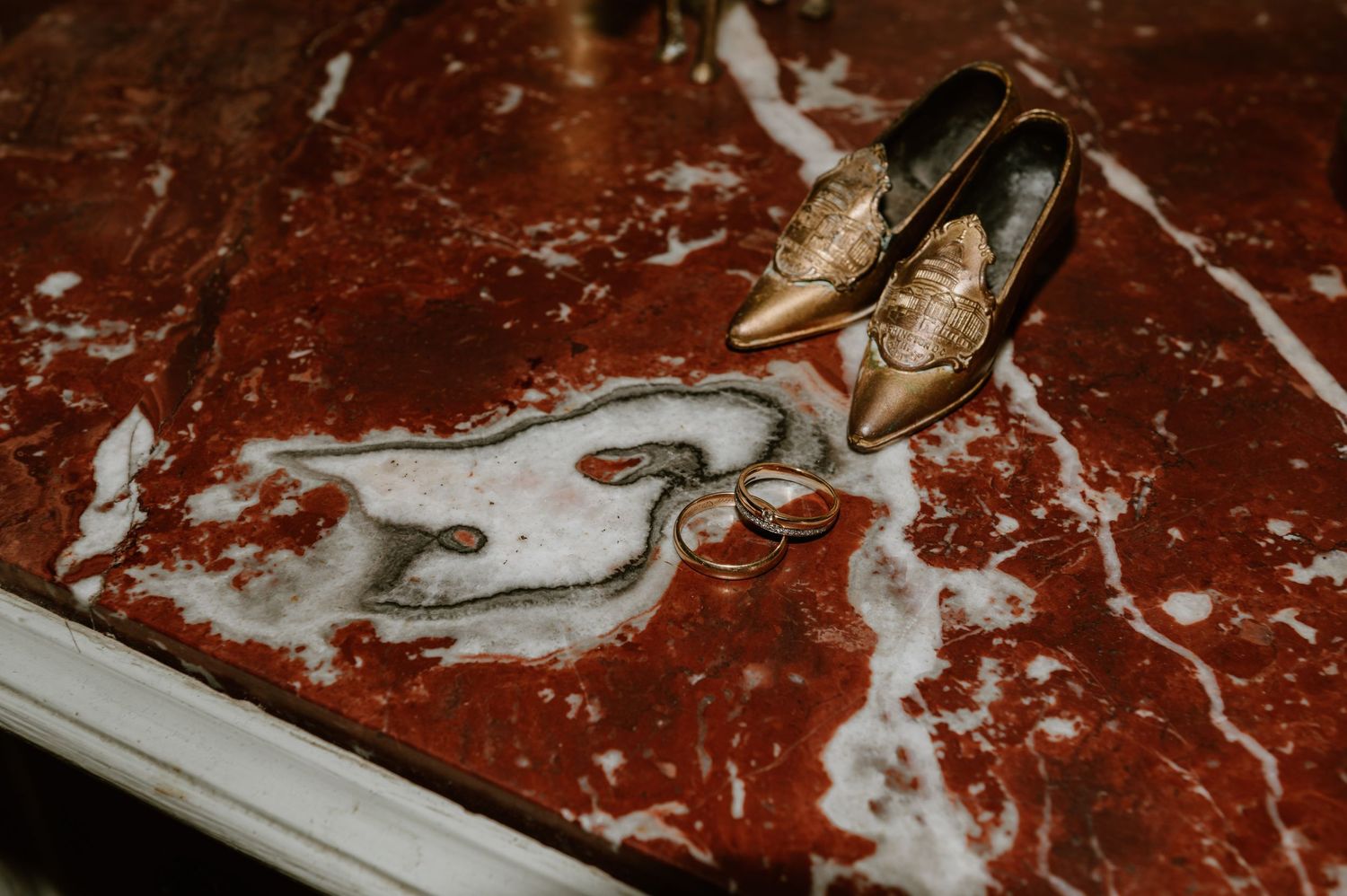 A brass shoe decor and rings on red marble