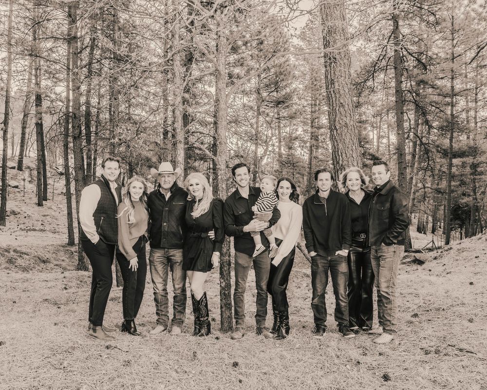 A group of people in winter attire pose together in a snowy forest setting.