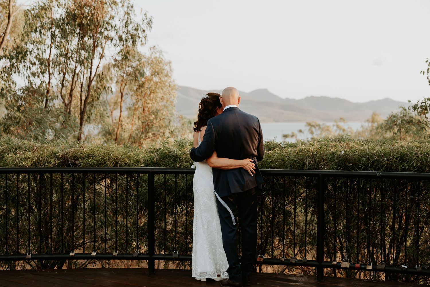 Couple embracing on awoonga dam balcony overlooking mountain landscape.