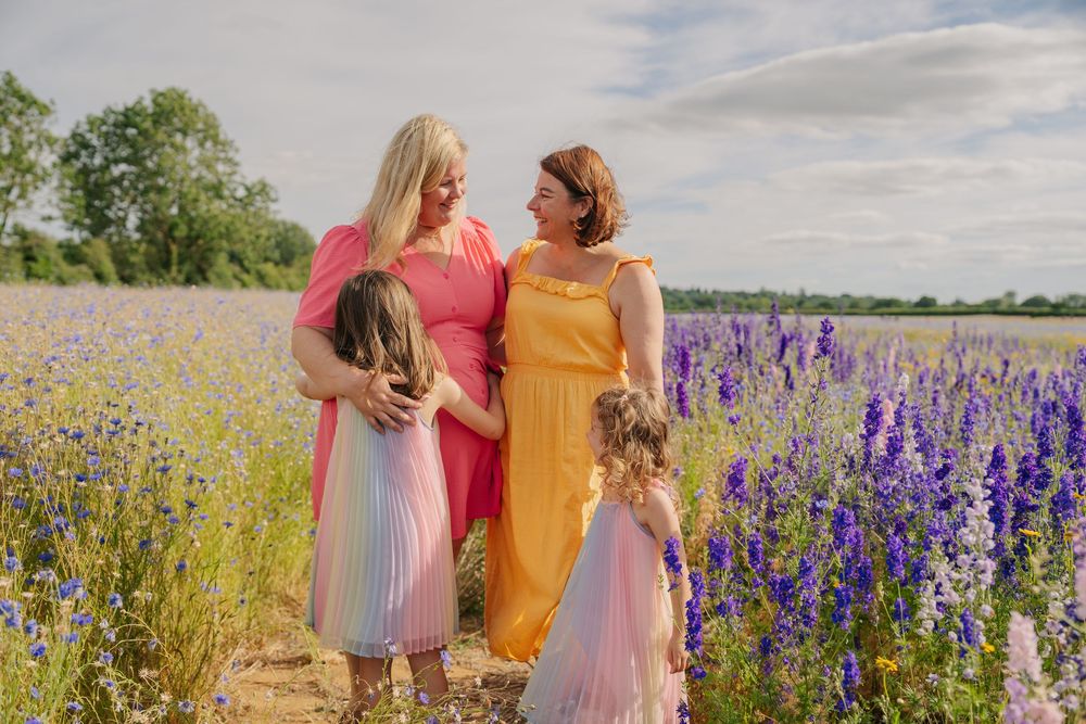 Two women in colorful dresses with young girls in a blooming lavender field on a sunny day.