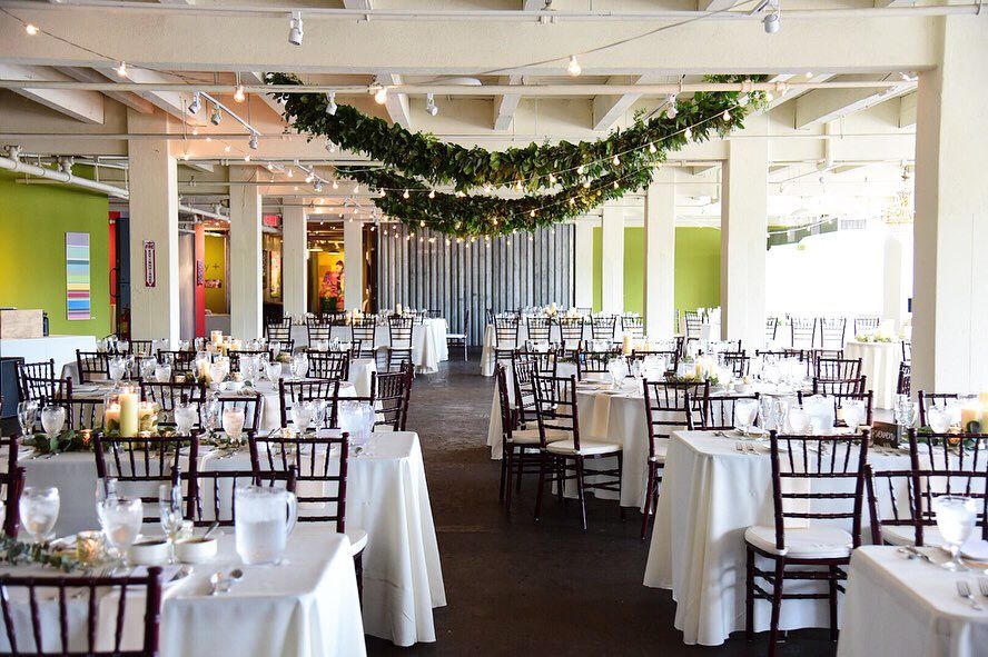 Modern reception venue decorated with hanging greenery and dark wooden chairs for elegant event.
