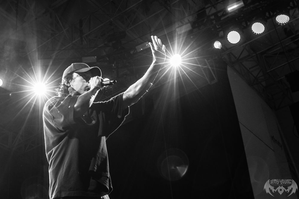 Black and white concert photo with stark spotlights creating dramatic silhouettes on stage.