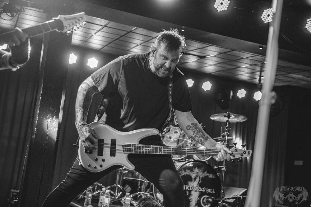 Bass guitarist performing on stage under dramatic concert lighting.