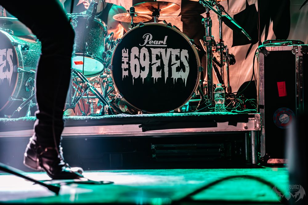 Pearl drum kit on stage with green stage lighting and band equipment.