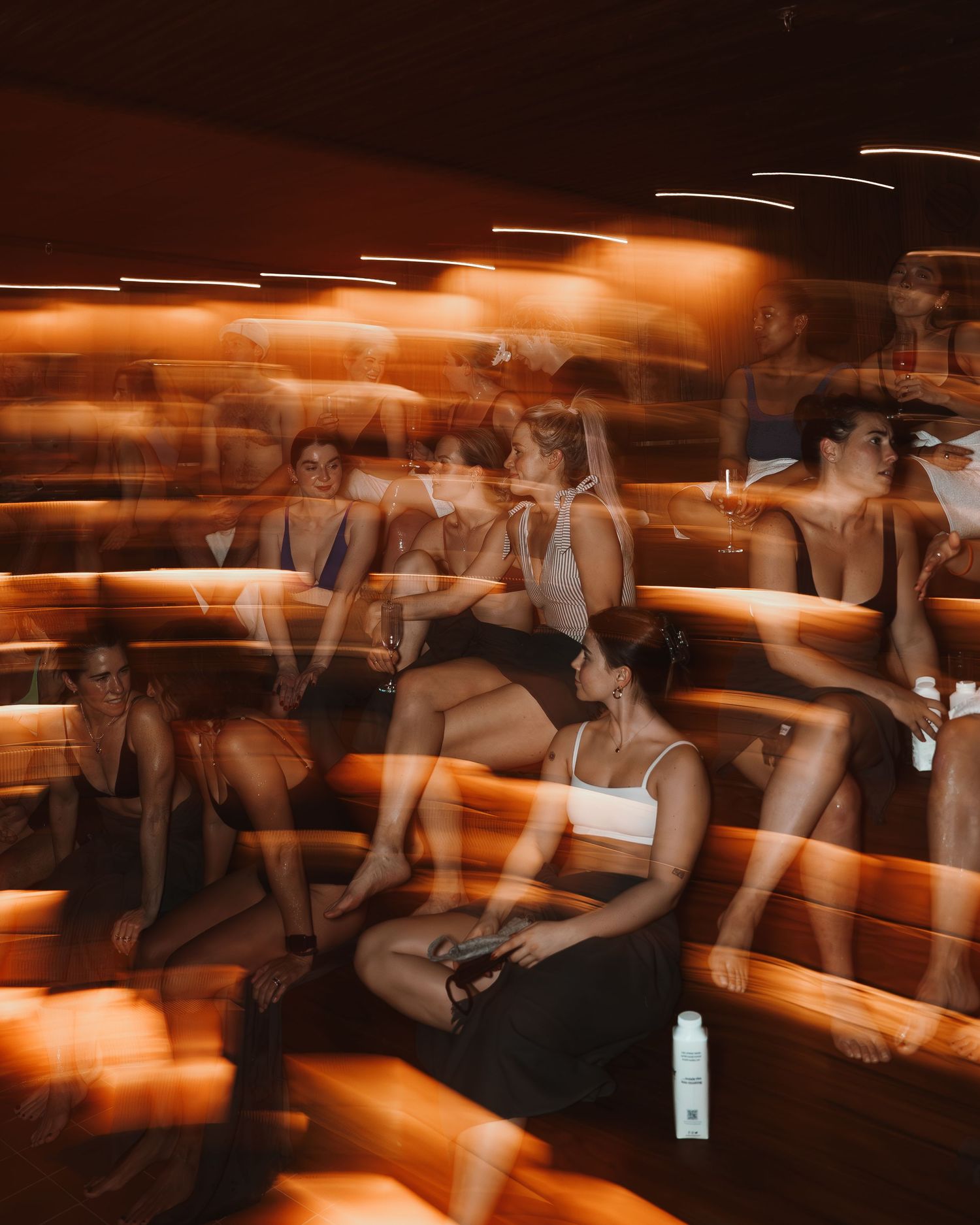Multiple people participating in a fitness class with motion blur and warm orange lighting in a studio setting.