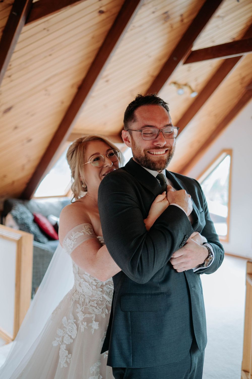 A tender first look moment between a bride and groom in a rustic wooden A-frame venue.