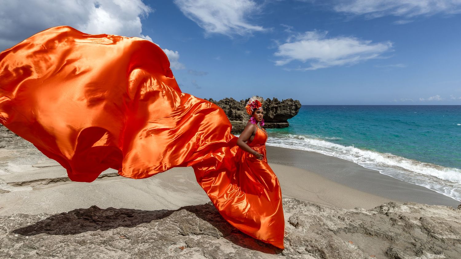 Emerald green flowing dress catches wind during sunset by the ocean.