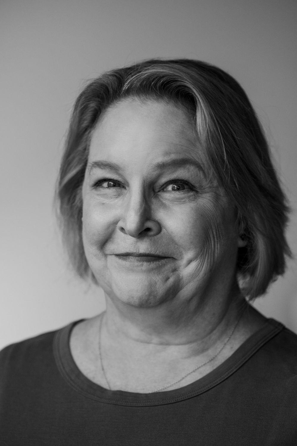 Black and white portrait photograph of a mature person with short hair smiling warmly at the camera.