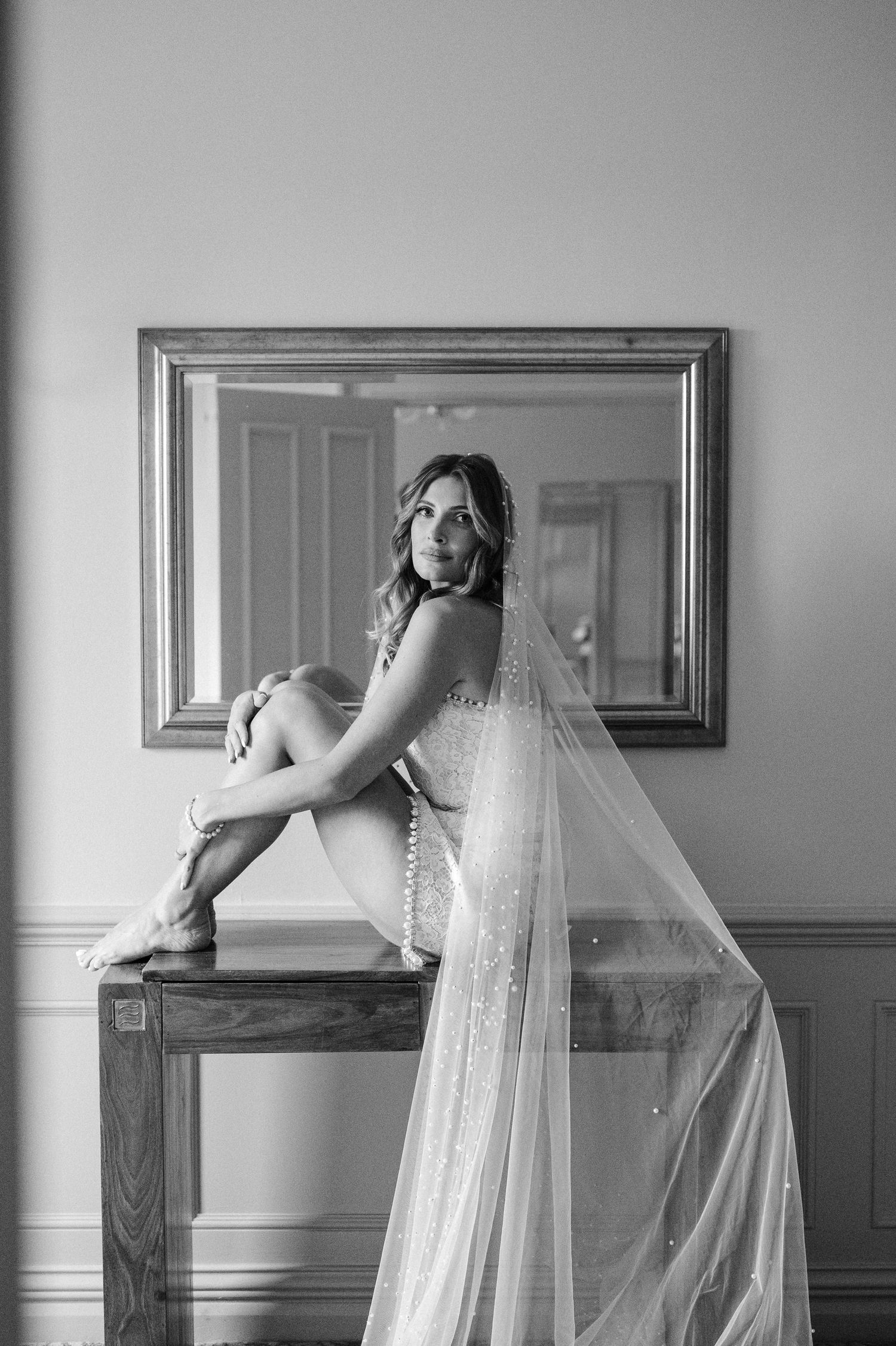 A black and white photo sequence shows a bride in a flowing dress and veil posing artistically against a wall, at Surrey wedding venue.