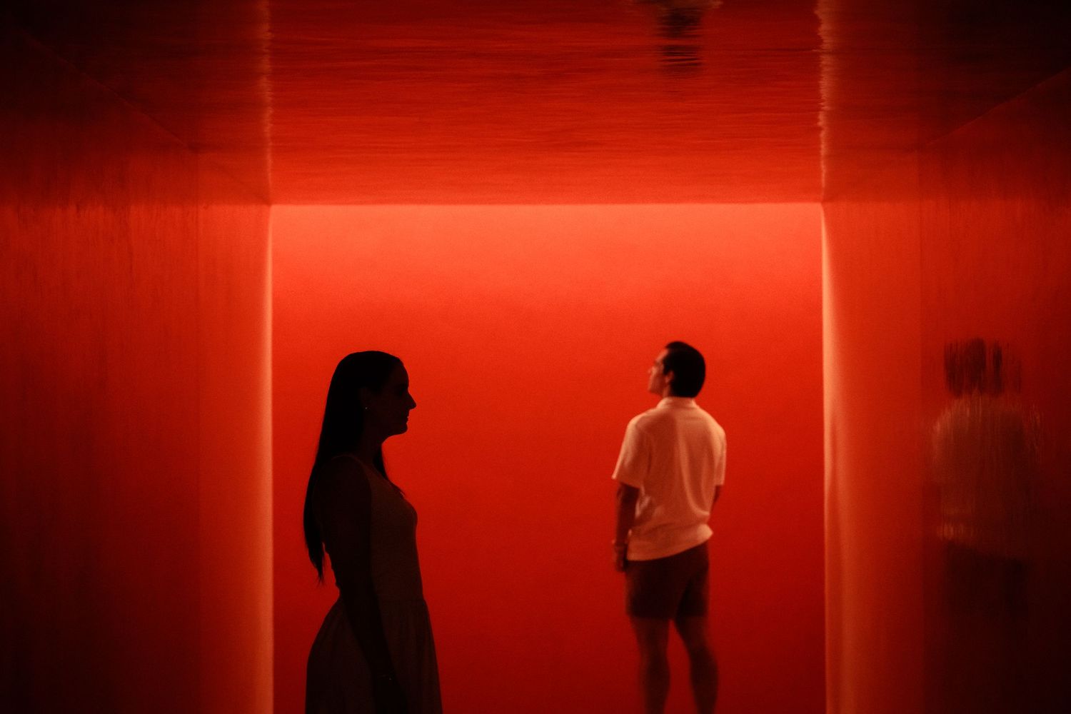 Artistic red-lit hallway creates dramatic silhouettes for wedding photography.