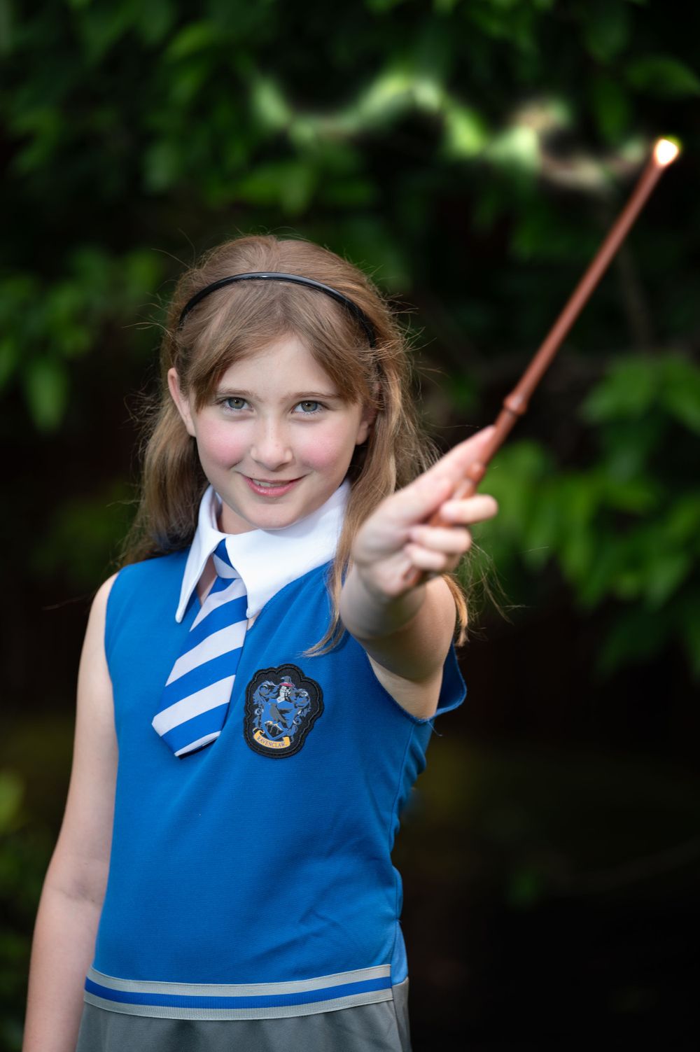 Young student in Ravenclaw-inspired costume holding a wand in Harry Potter themed photo.