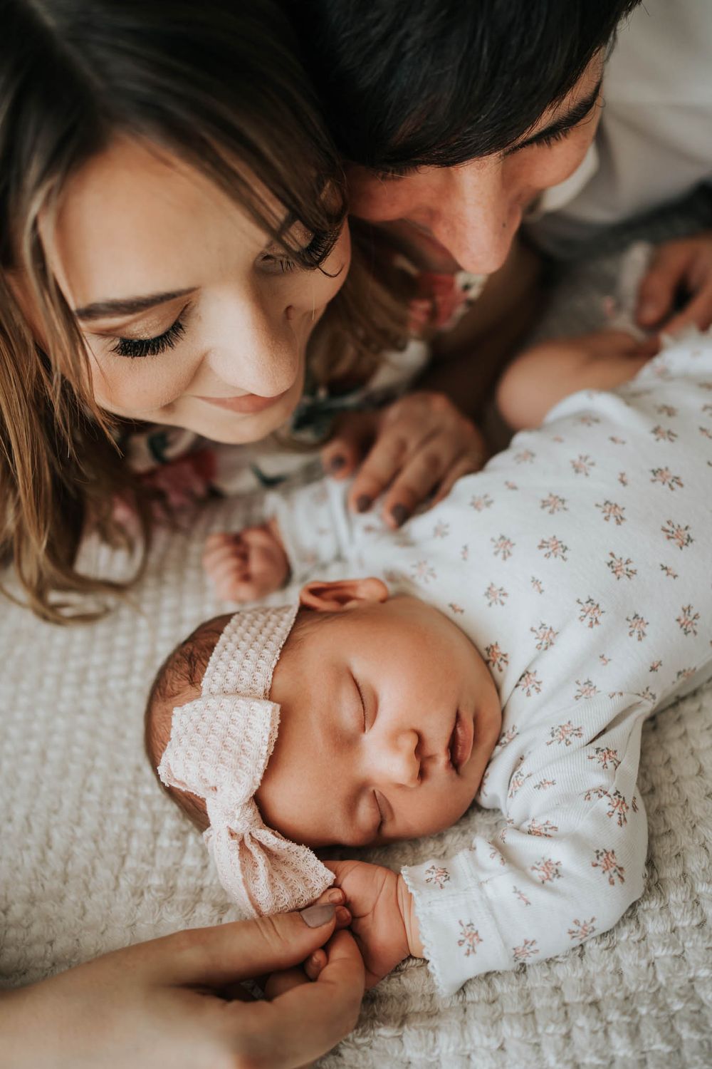noworodek leży na łóżku, tata i mama na niego patrzą - sesja noworodkowa Kraków