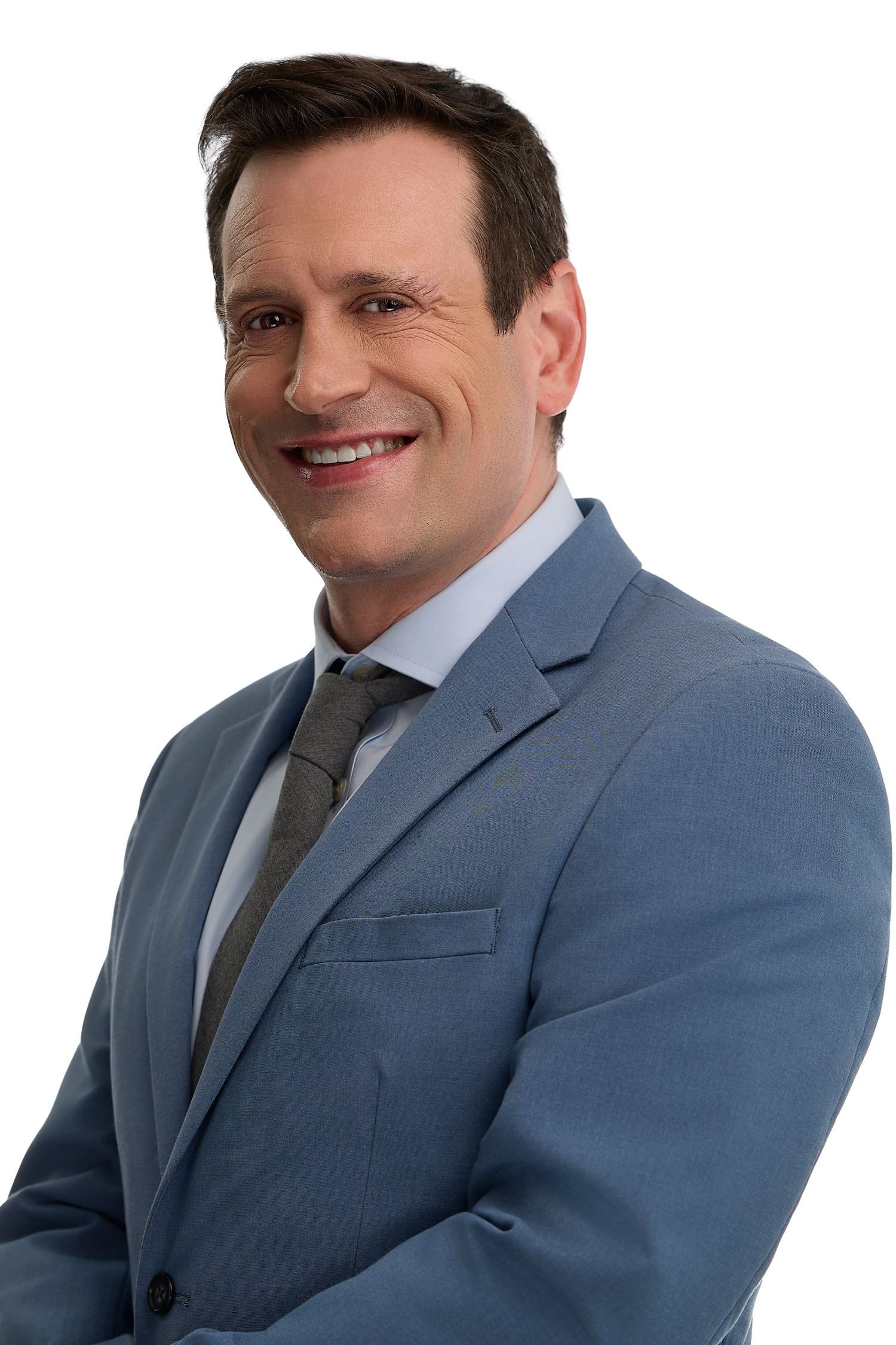 Smiling middle-aged businessman in blue suit and gray tie with arms crossed on white background.