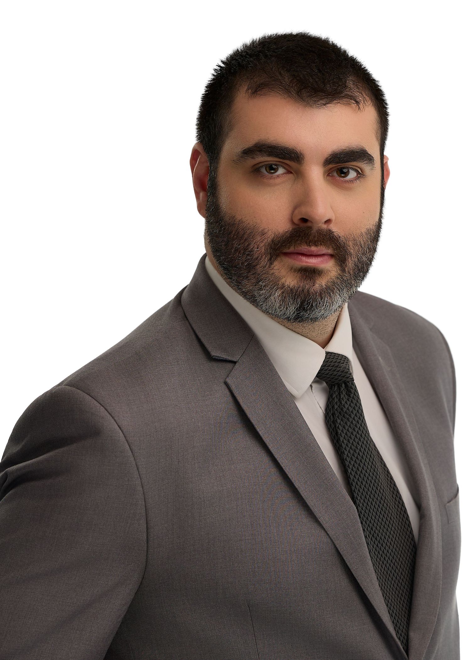 Professional man in gray suit and dark tie with beard, formal business headshot on white background.
