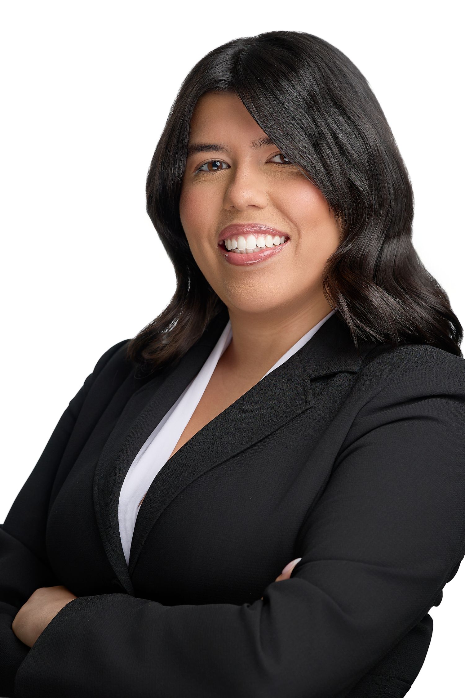 Professional businesswoman in black blazer smiling confidently with arms crossed against white background.