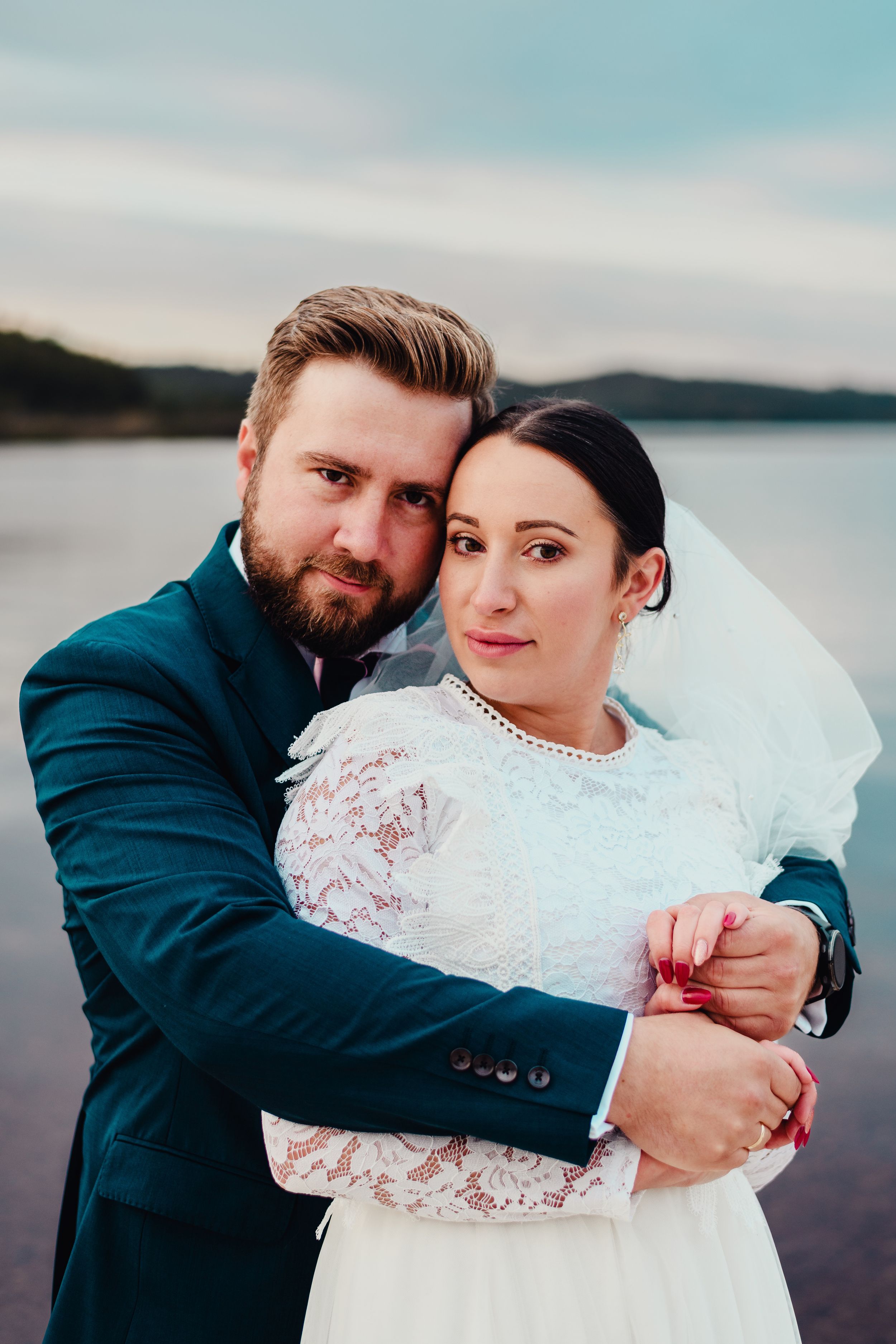 Romantic sunset portrait of newlyweds by a lake.