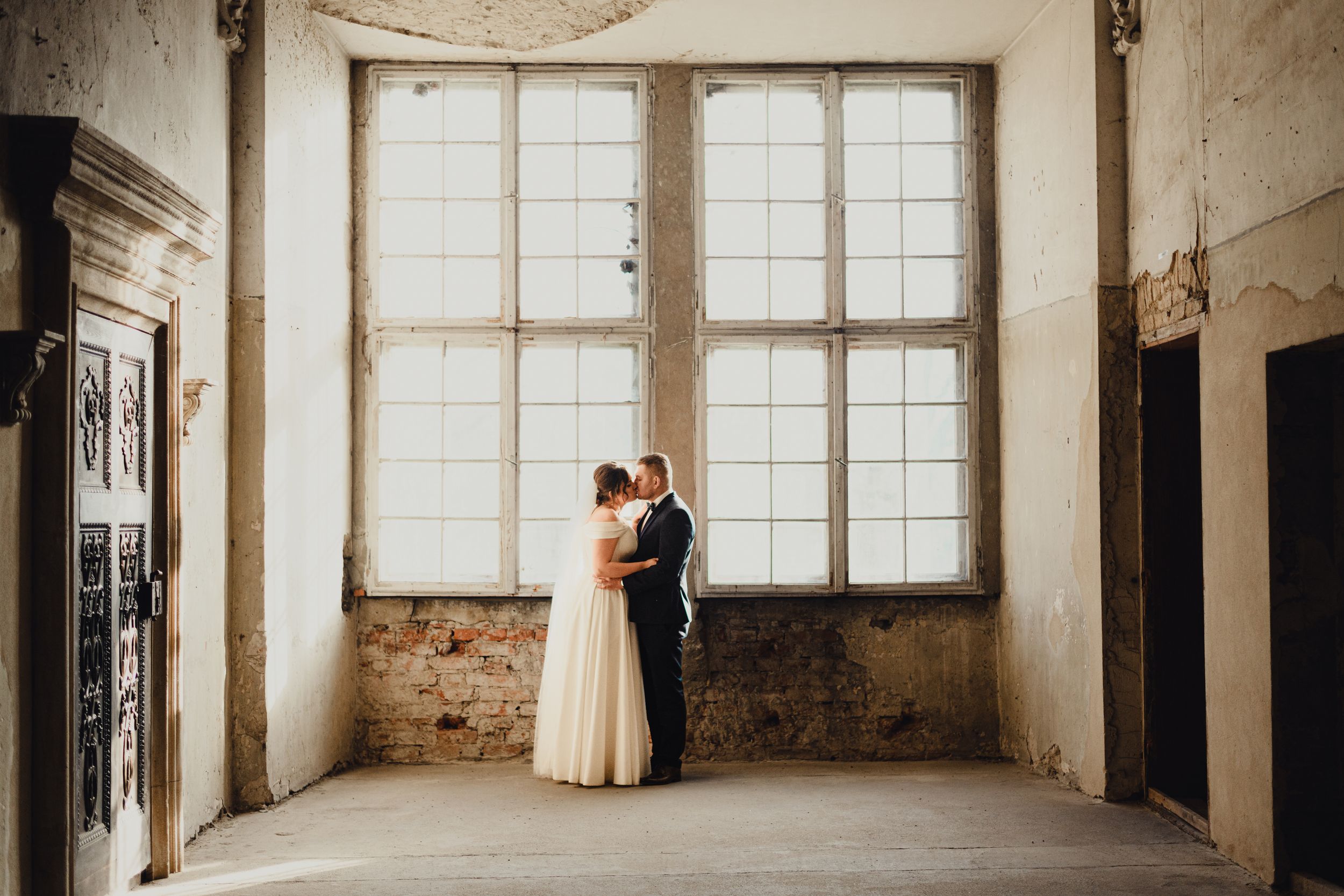 Industrial wedding venue interior with large windows and exposed brick walls.