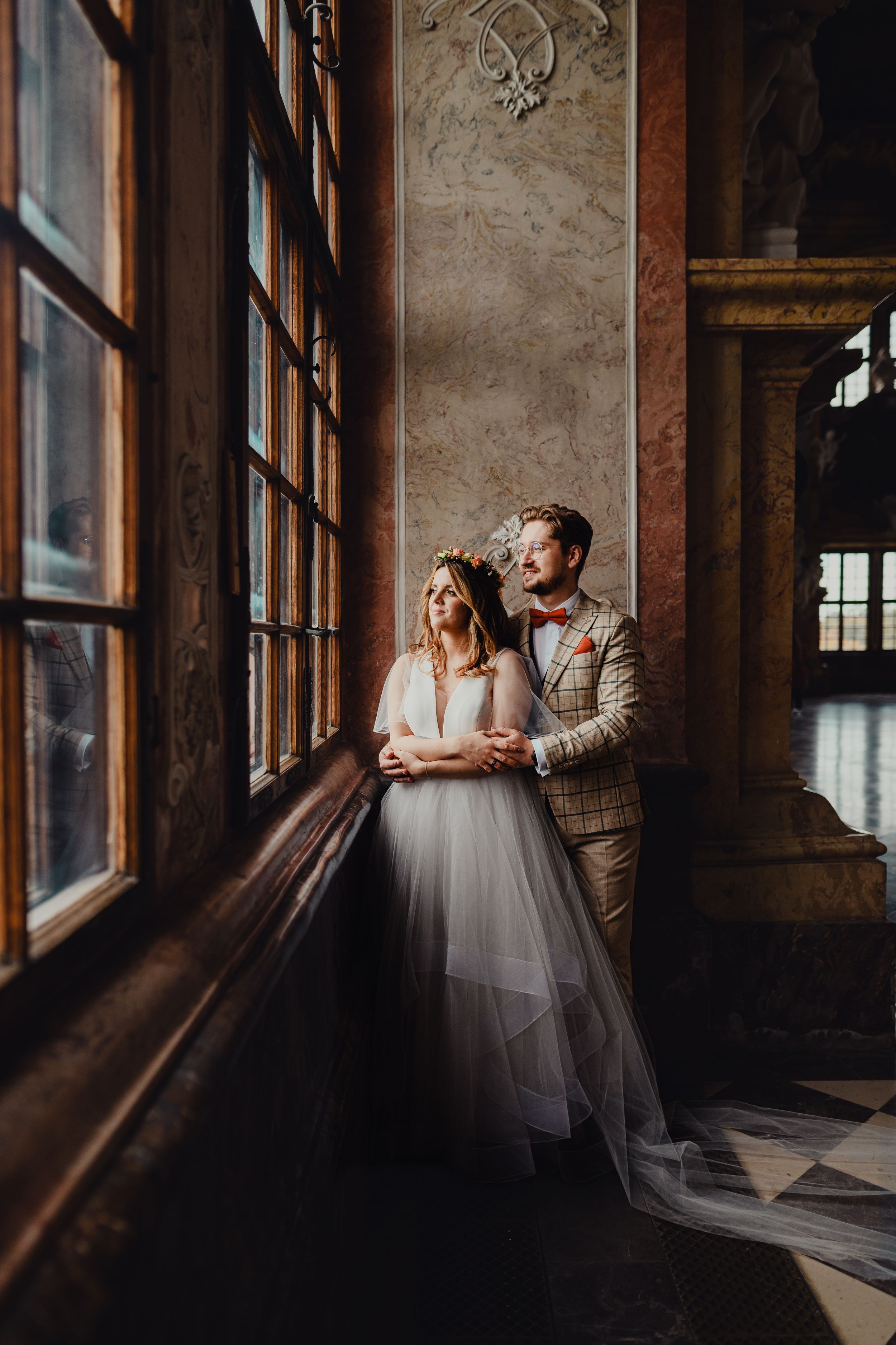Romantic wedding portraits taken in an industrial venue with dramatic window lighting.