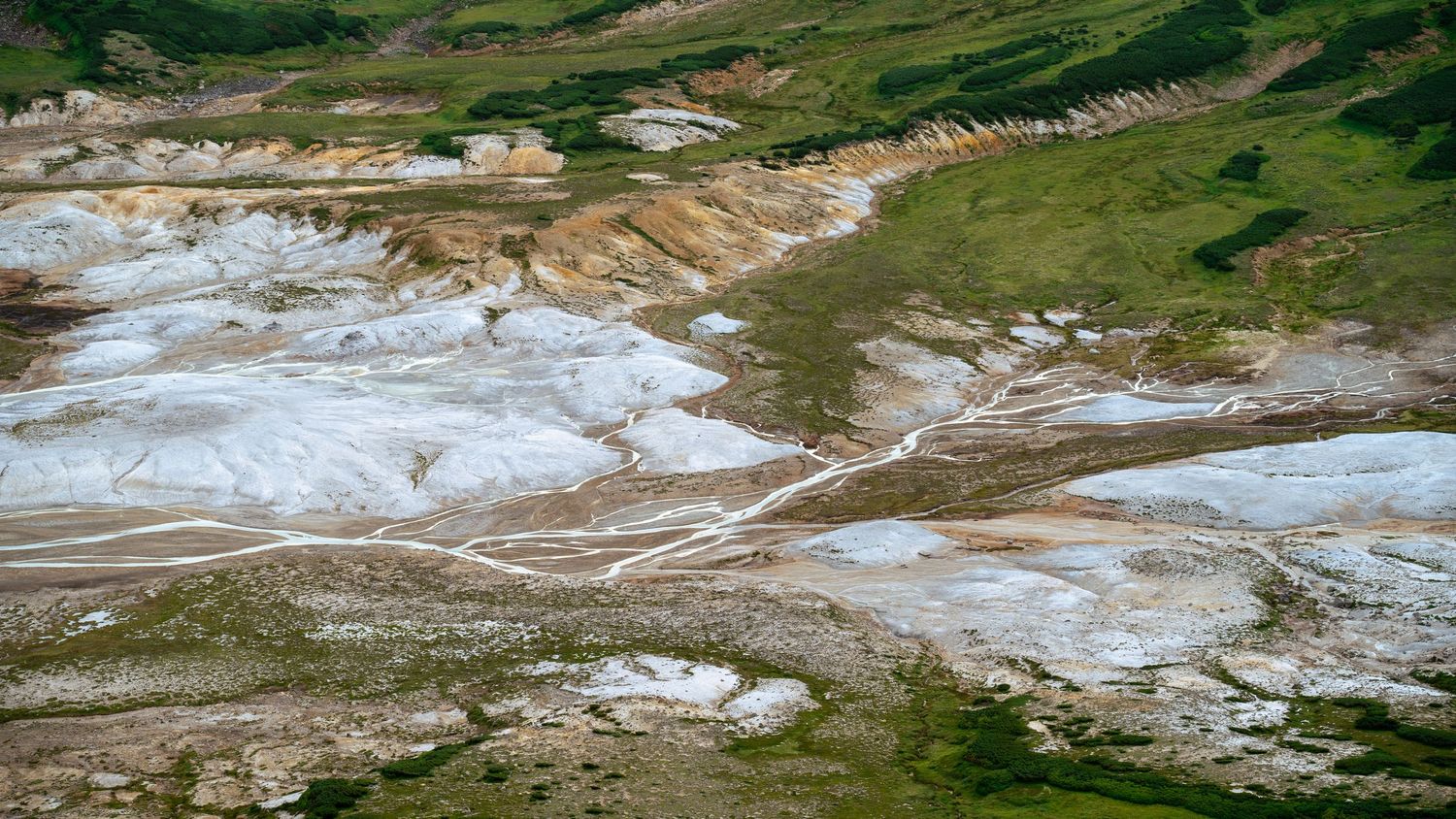 Aerial view of mineral deposits and geothermal features in mountainous terrain.