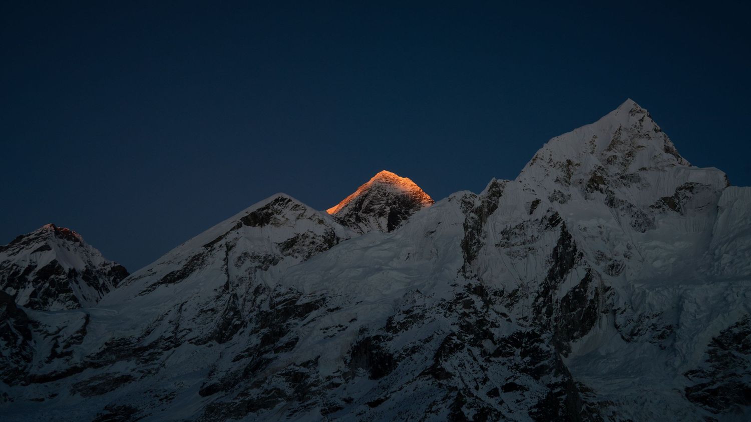 Mountain peaks at dusk with the last rays of sunlight illuminating the snow-covered summits.