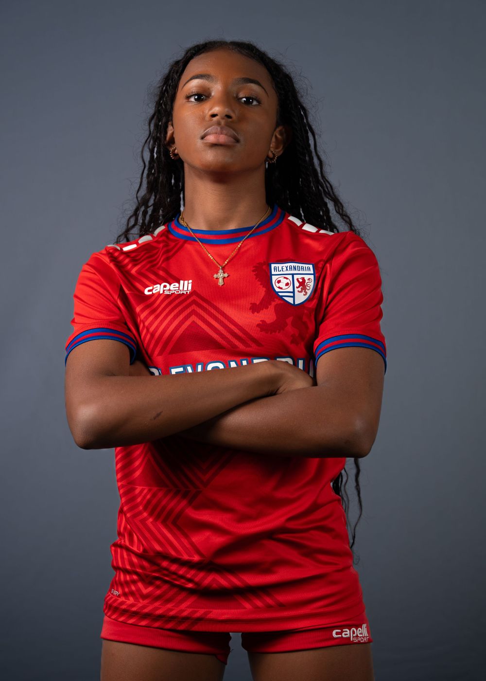 Soccer player in red Alexandria uniform stands with arms crossed.