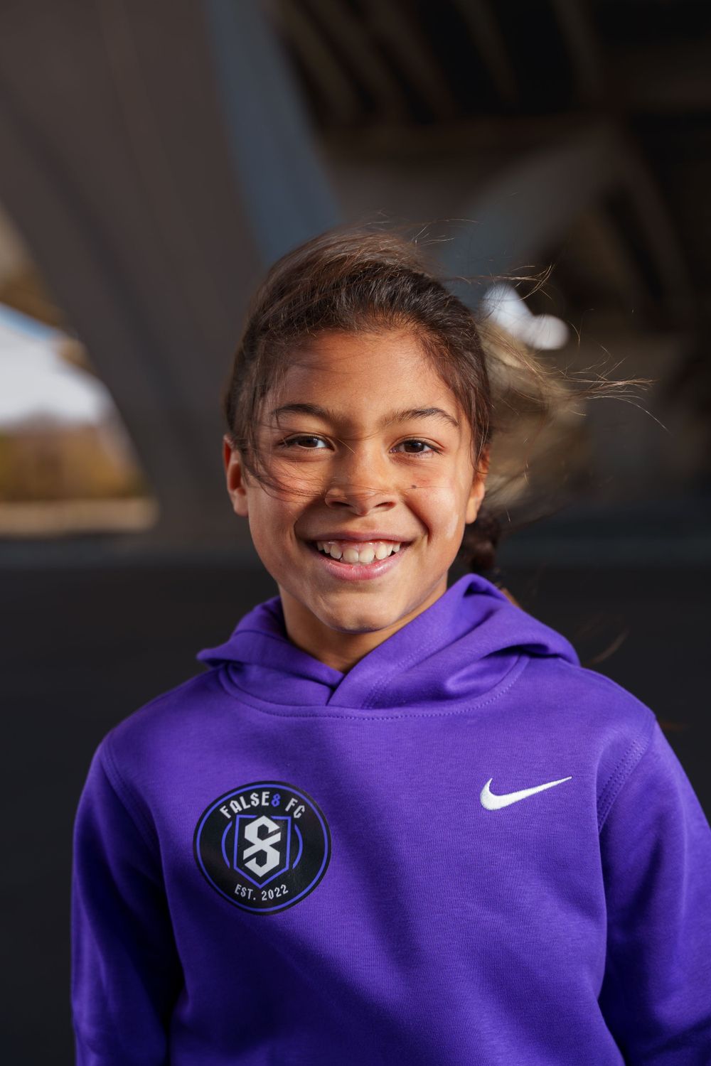 Youth athlete wearing purple Nike hoodie with Pulse FC logo.