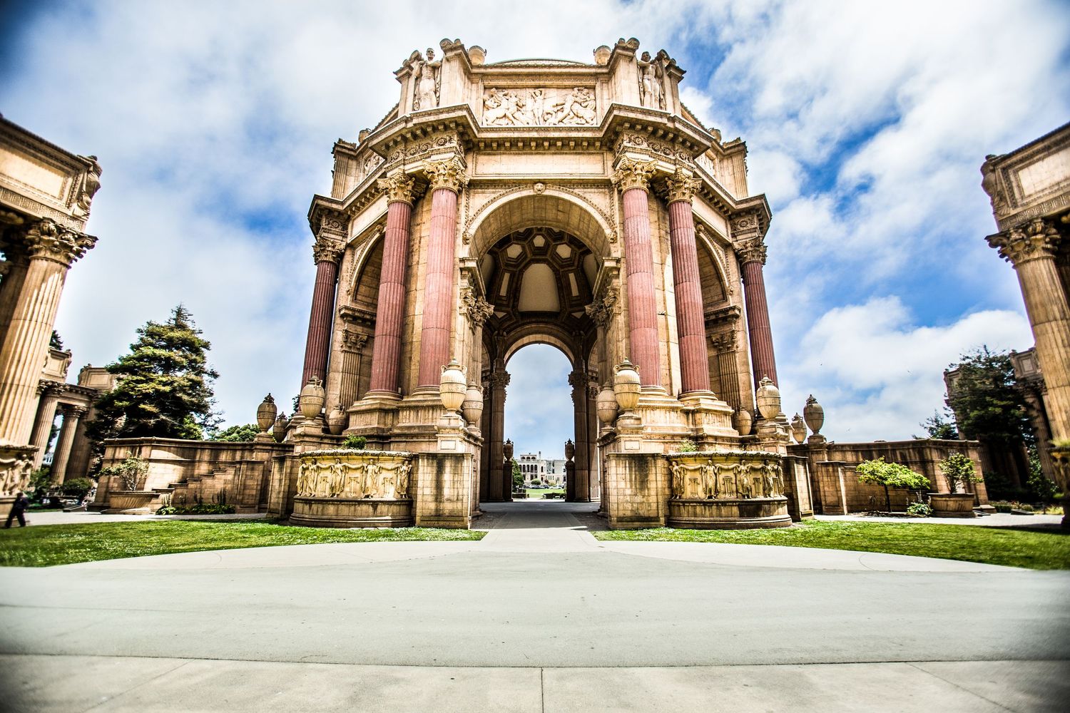 The Palace of Fine Arts features a grand Greco-Roman style rotunda and colonnade against a blue cloudy sky in San Francisco.