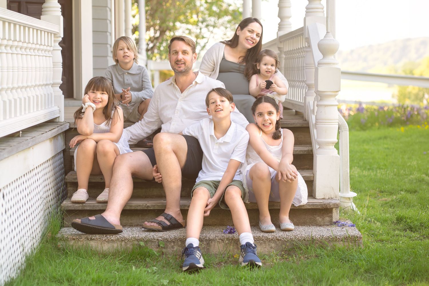 Multi-generational family group poses outdoors on grassy field.