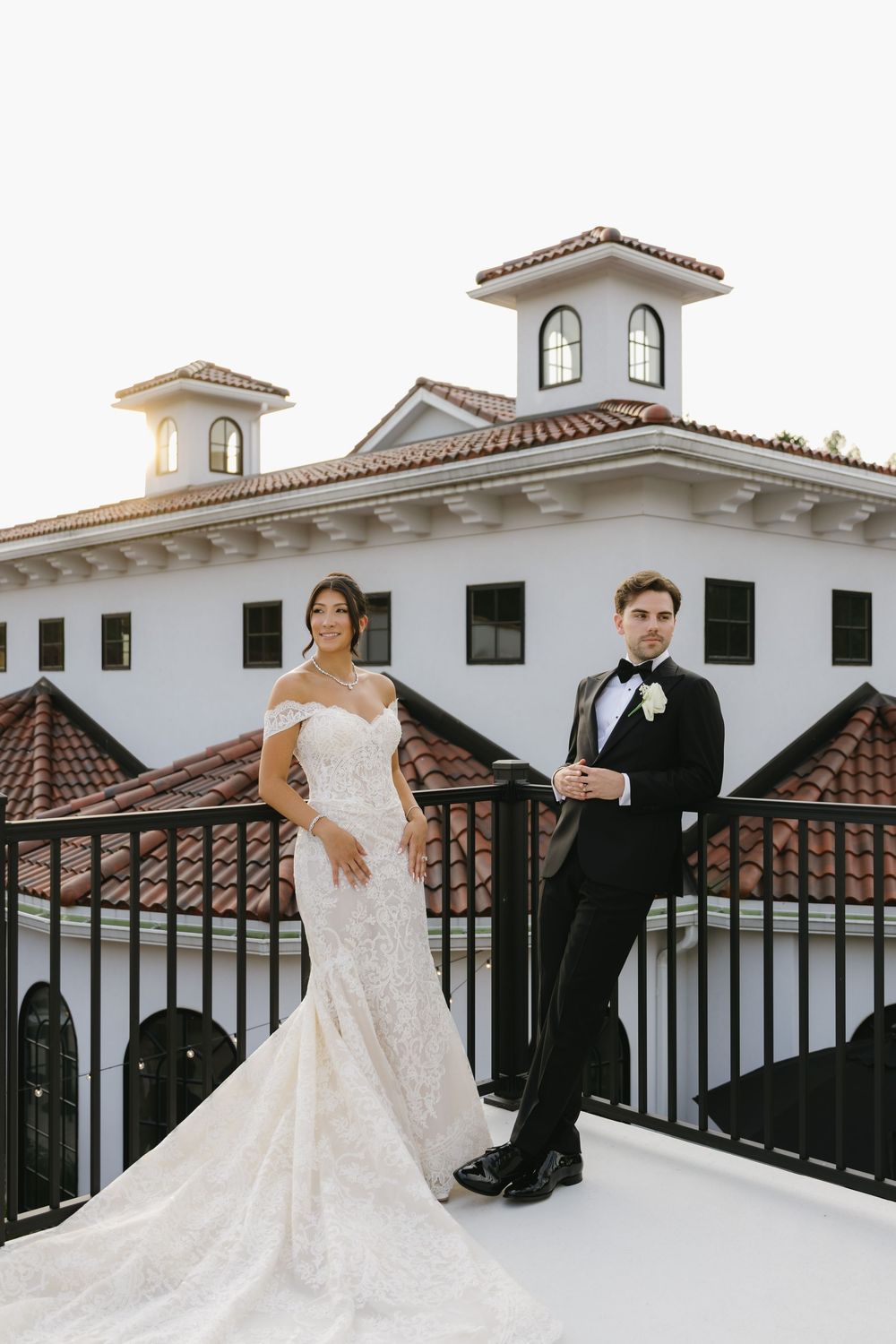 Couple poses on rooftop terrace with Spanish colonial architecture.