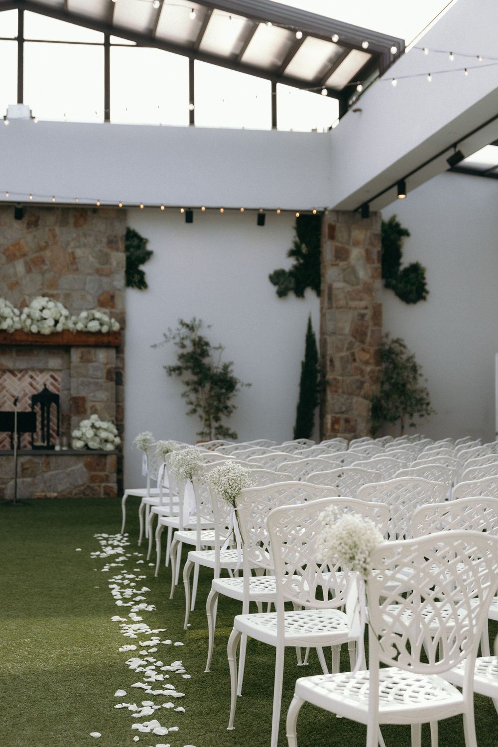 Indoor wedding venue with white chairs arranged in rows and stone wall details.