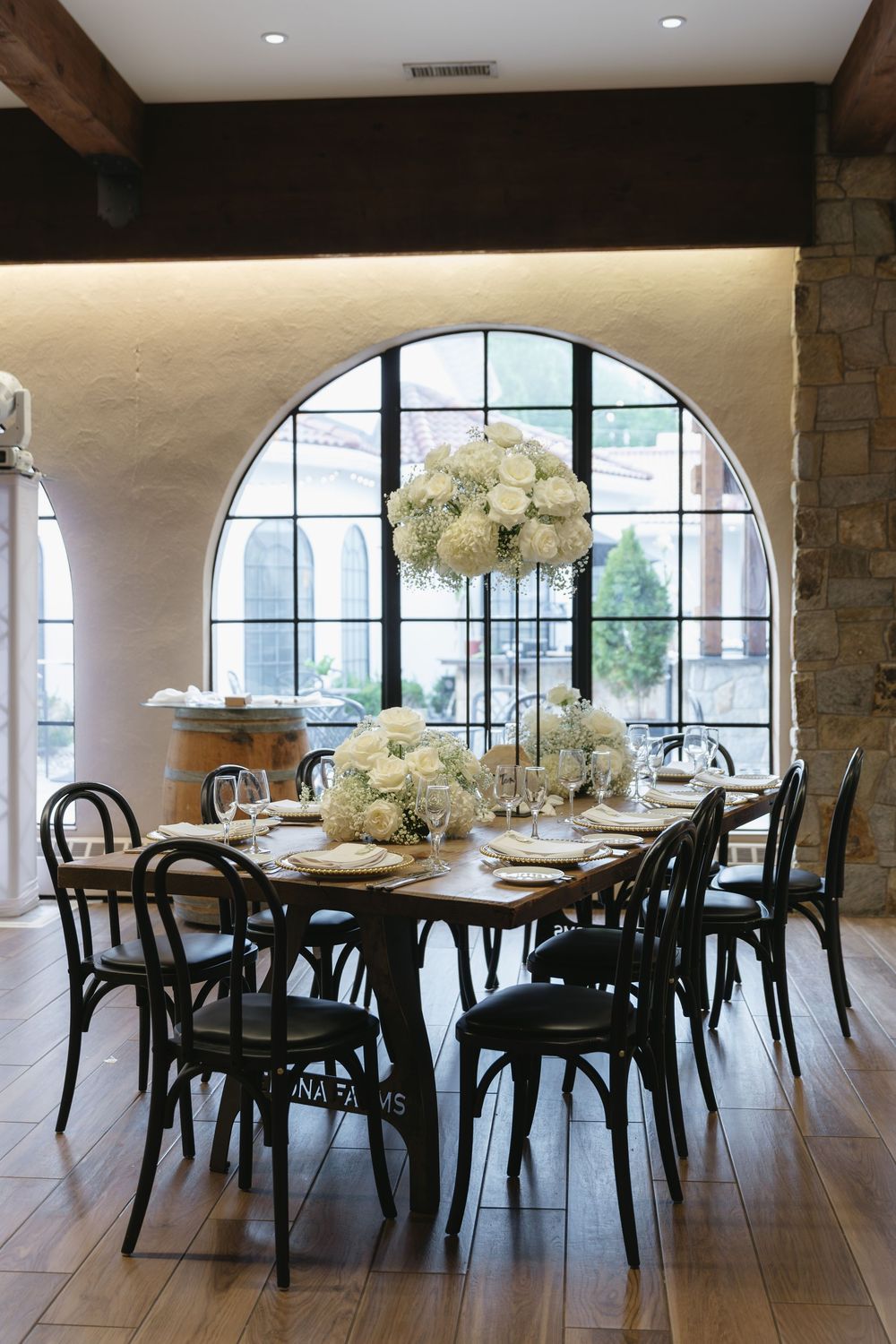 Reception dining area with round tables, black chairs, and arched windows.