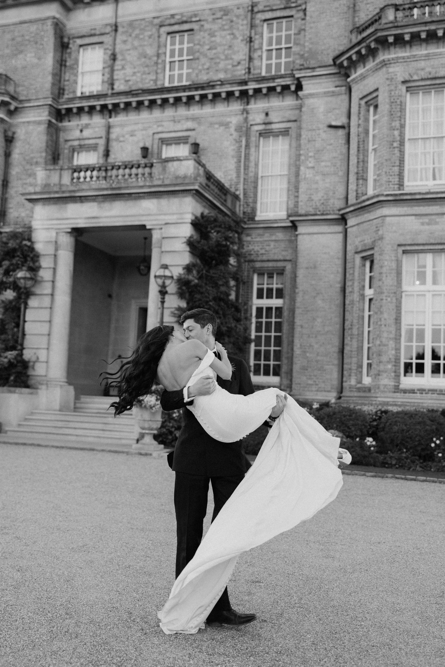 black and white portrait of a groom carrying her bride