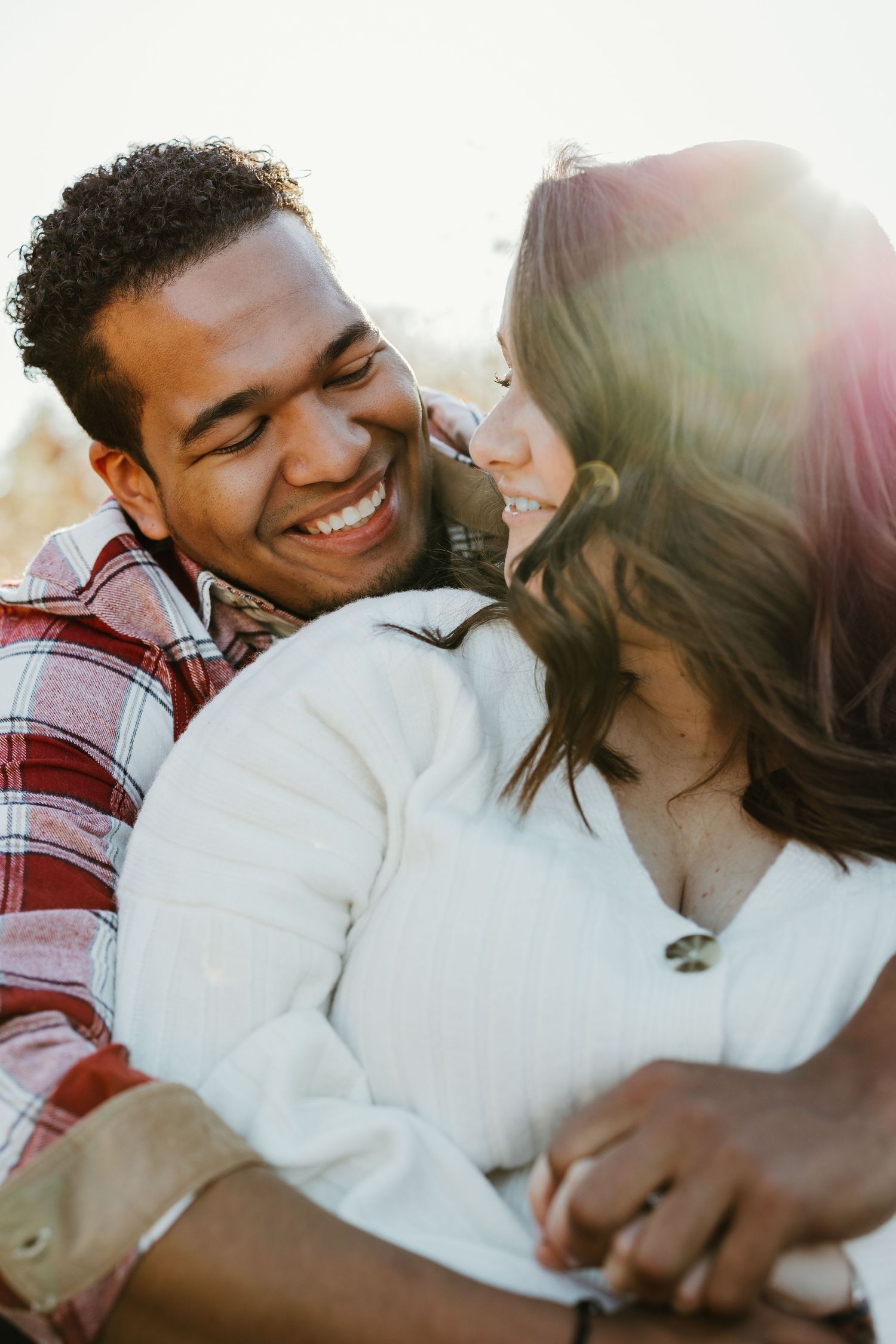 Laughing couple shares intimate moment in warm sunset light.