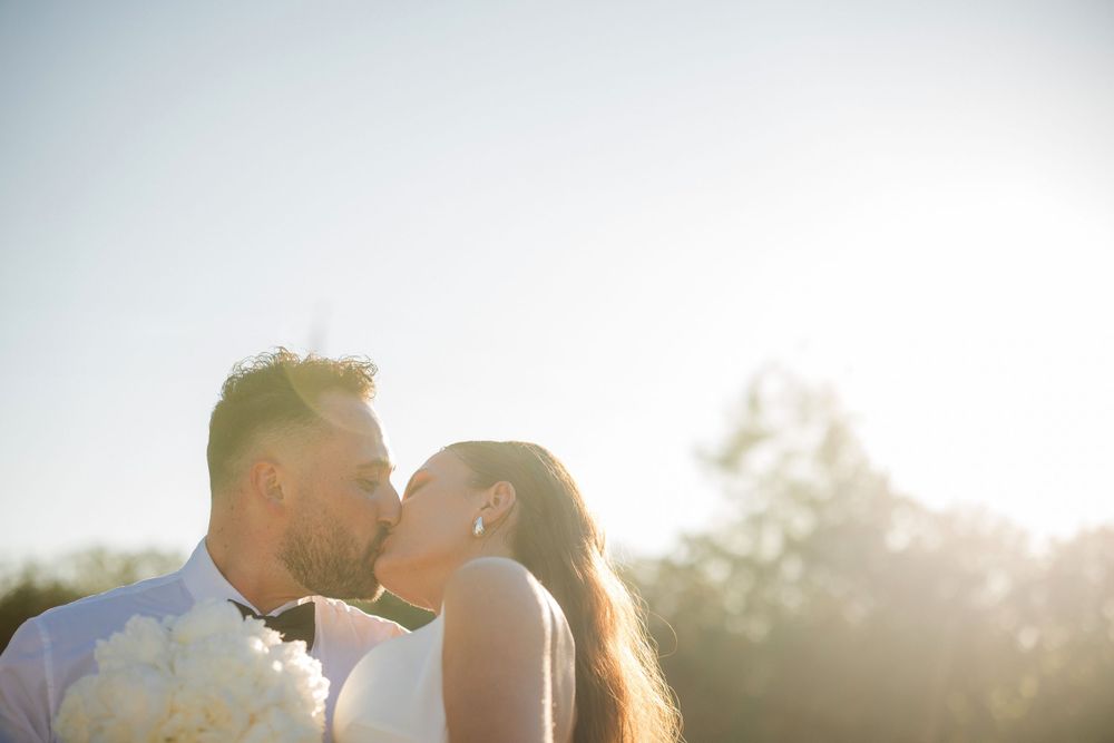 Un couple s'embrasse en plein soleil le jour de leur mariage.
