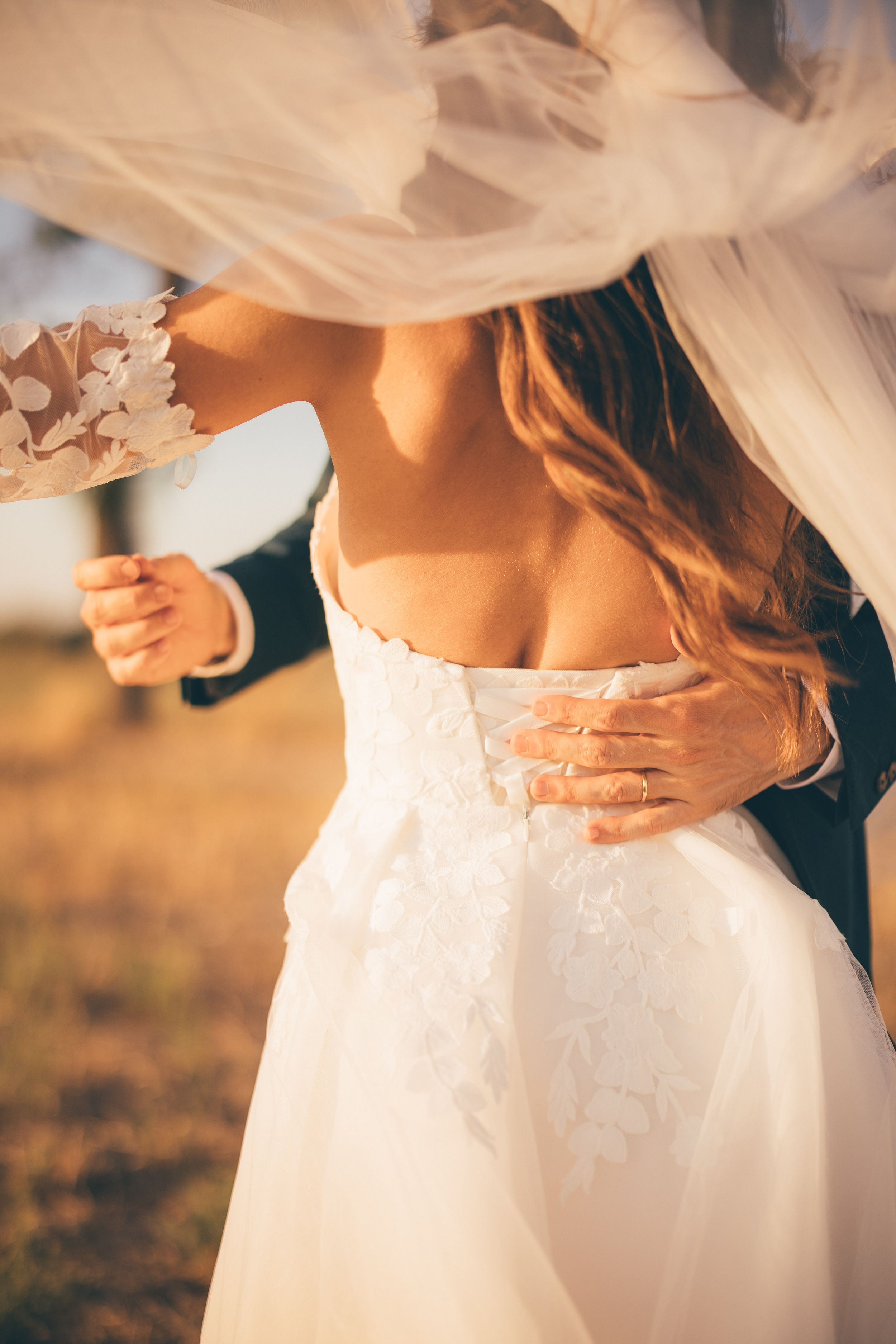 A romantic close-up shot of a bride's white wedding dress flowing in the sunlight during golden hour.