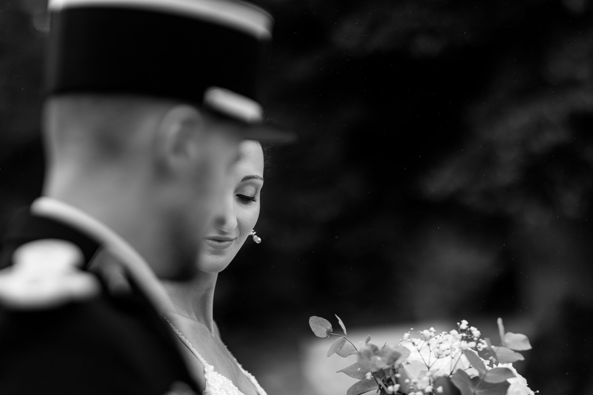 Black and white candid portrait of a couple at a military wedding ceremony.