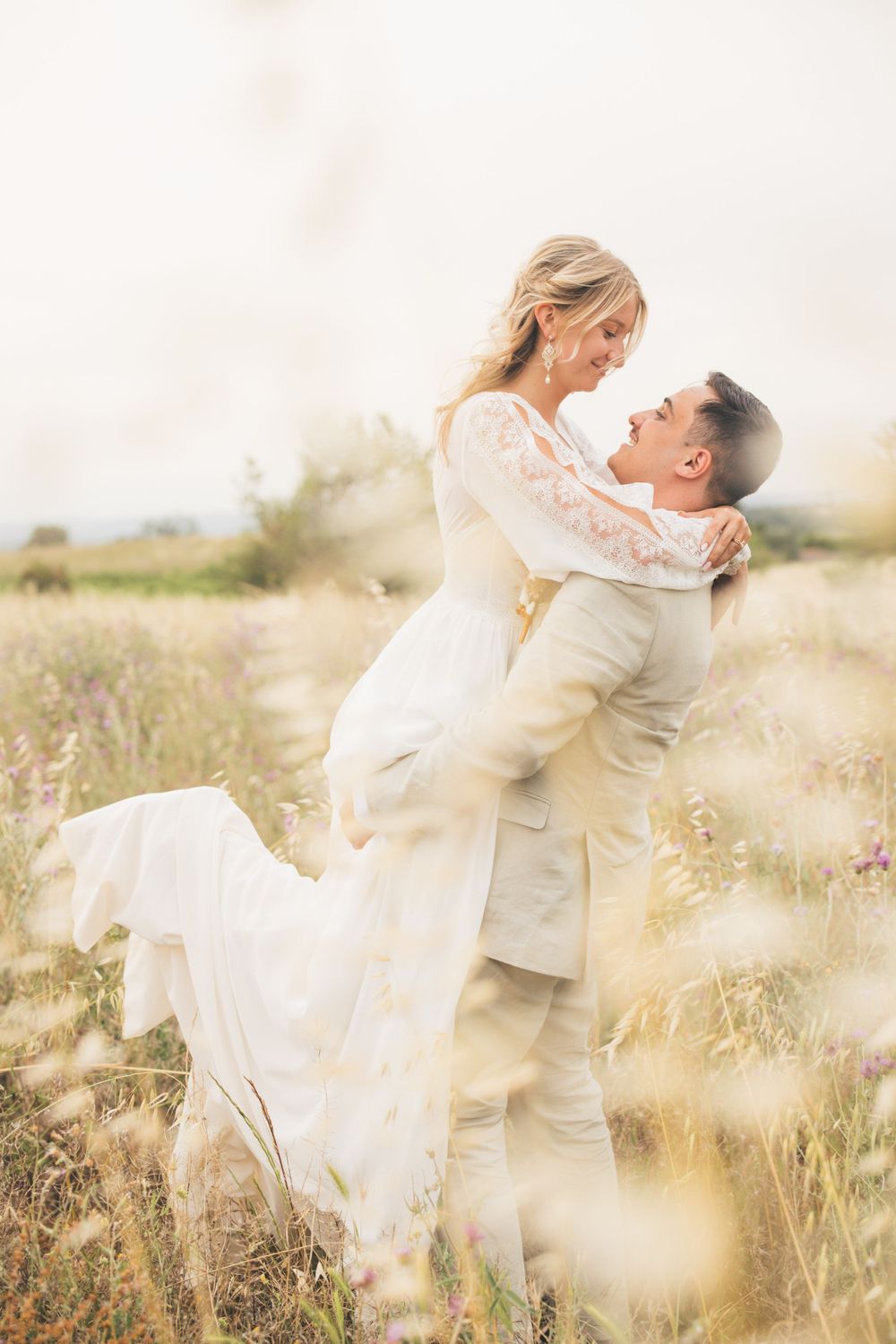 Couple romantique s'embrassant dans une prairie ensoleillée avec une robe de mariée blanche. Idée de photo de couple.
