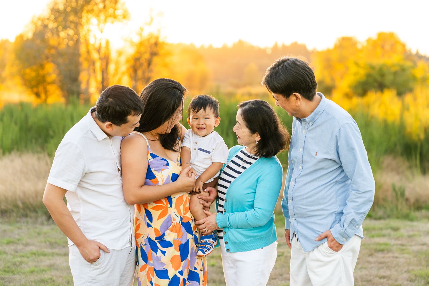 Family laughing with child at sunset in Marymoor Park.