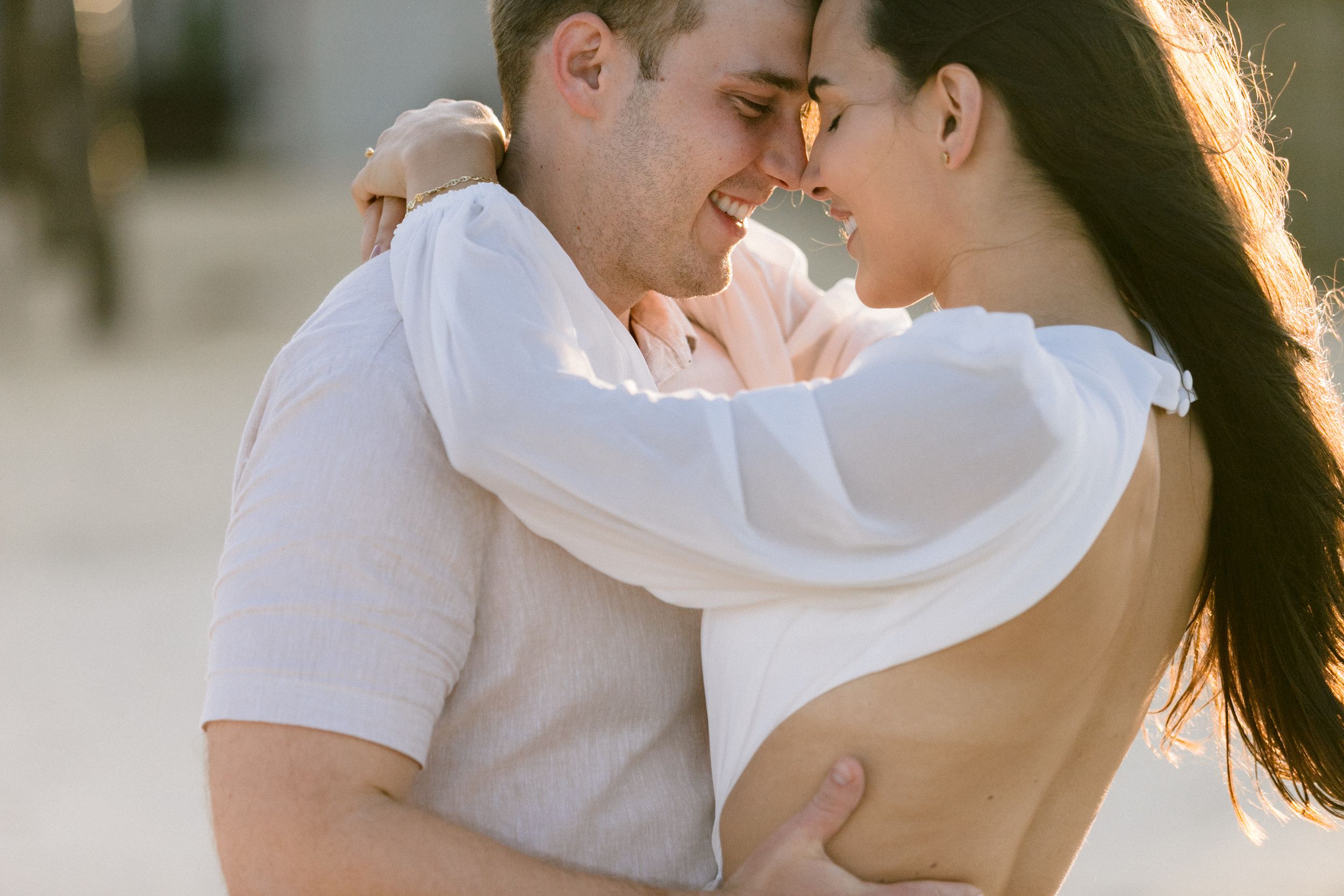 Intimate moment between couple in white clothing during sunset.