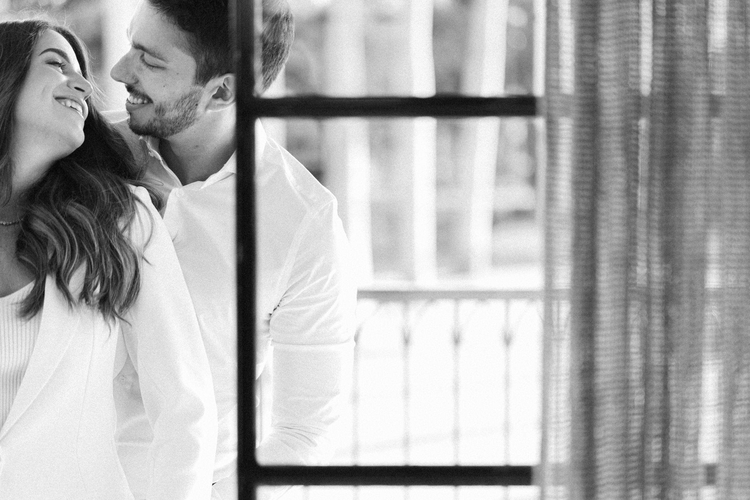 A tender black and white romantic moment near a window.