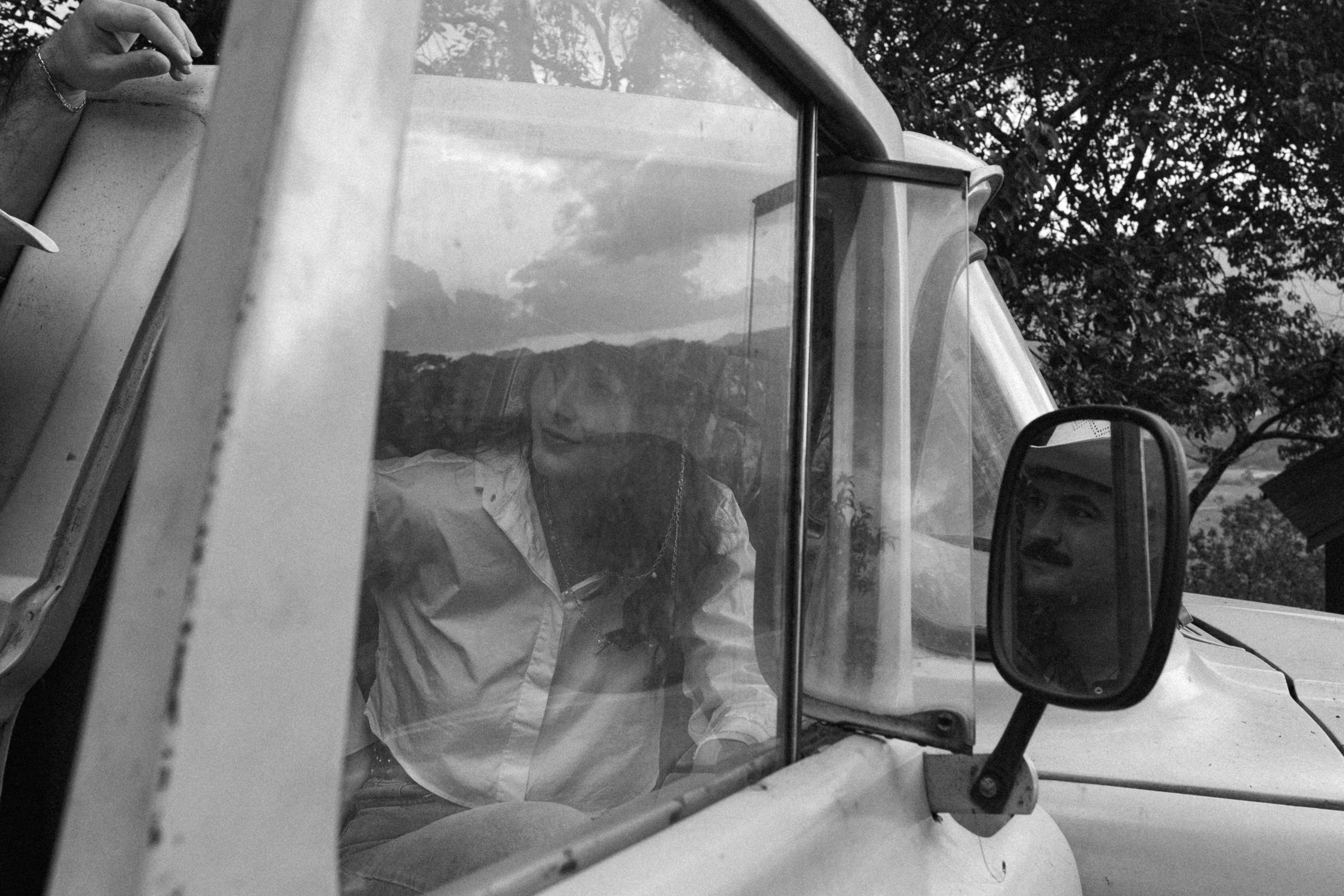 Black and white view through truck window showing interior and side mirror on rural road.