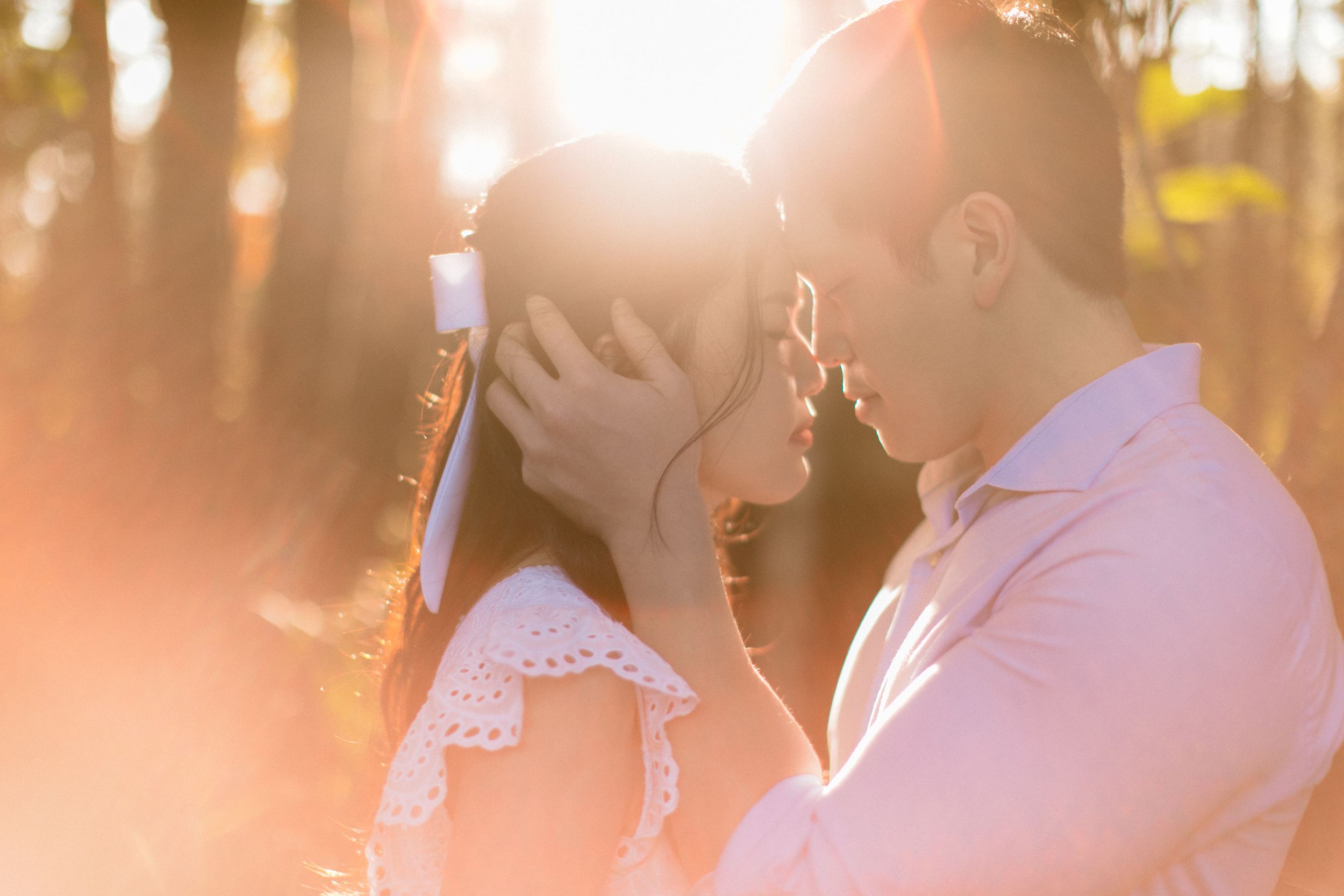 Romantic couple silhouetted against golden sunlight in an intimate outdoor moment.
