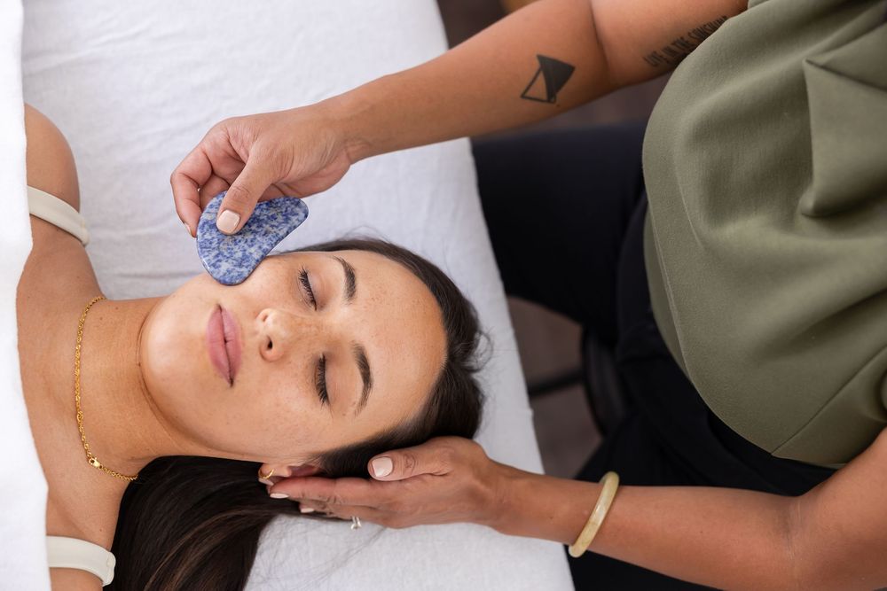 woman acupuncturist branding photo in Issaquah, WA with client acupressure treatment using gua sha tools on woman's face during session